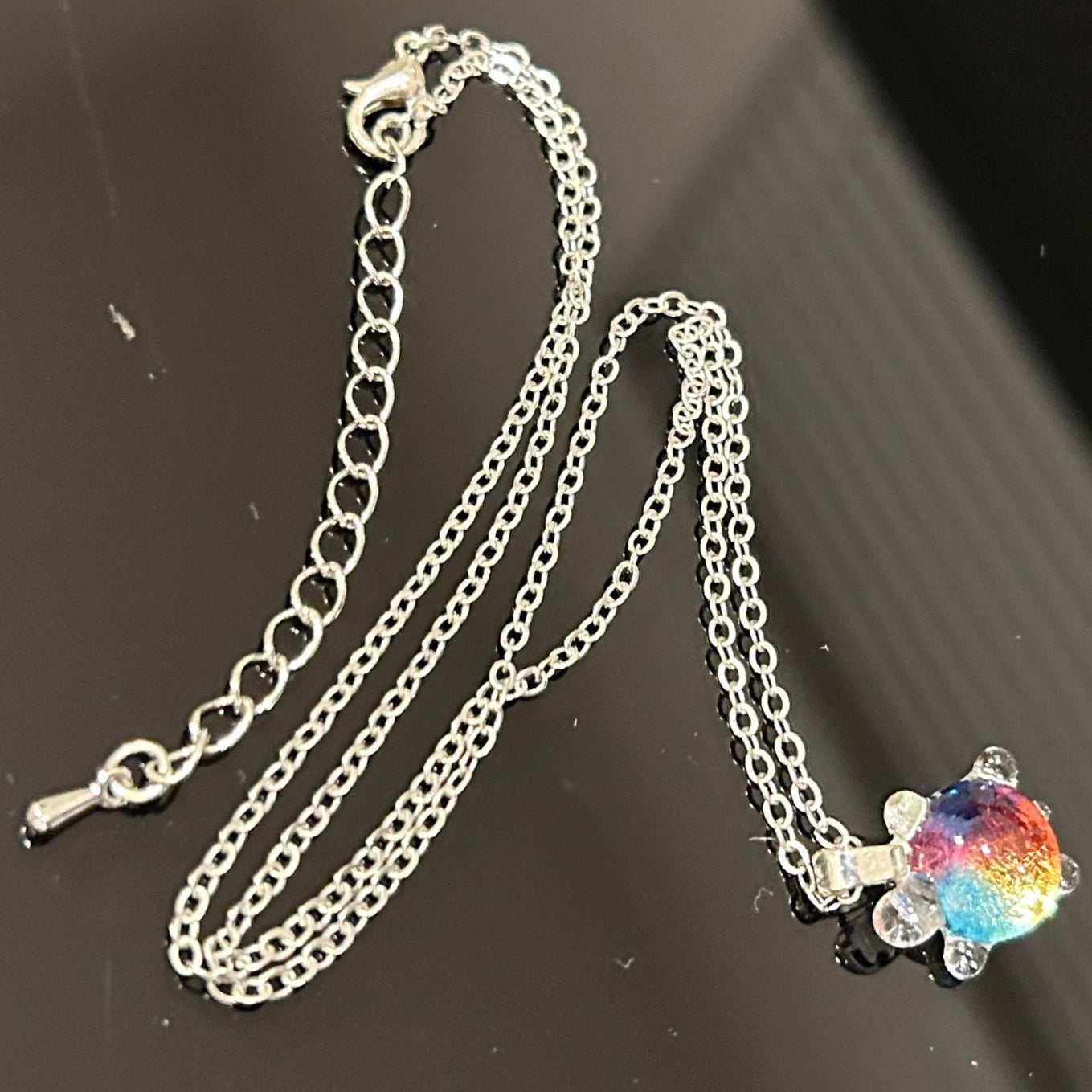 Handmade dichroic glass turtle pendant 1 inch showing color-shifting rainbow effects in blues purples oranges greens