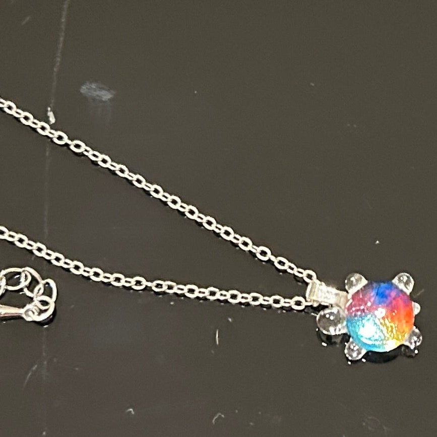 Handmade dichroic glass turtle pendant 1 inch showing color-shifting rainbow effects in blues purples oranges greens