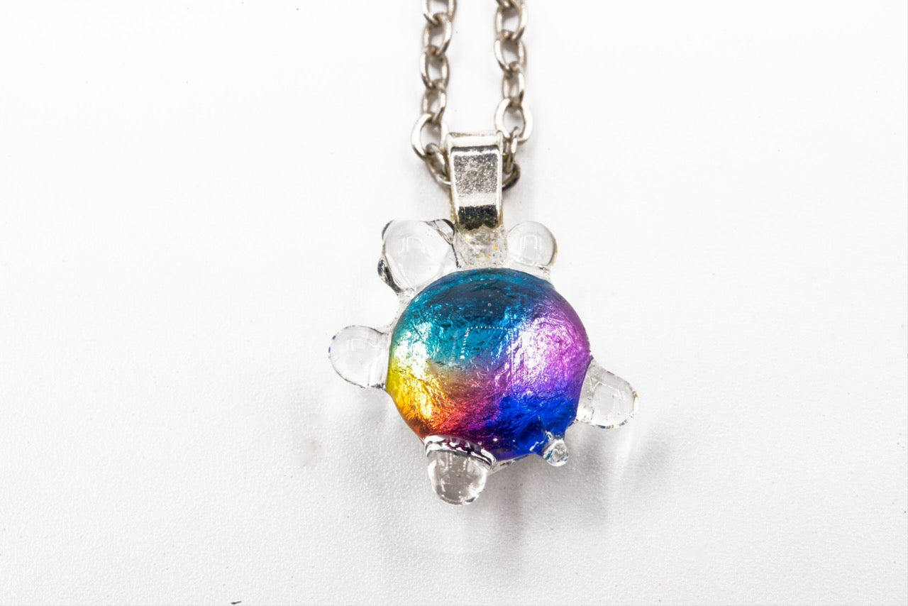 Handmade dichroic glass turtle pendant 1 inch showing color-shifting rainbow effects in blues purples oranges greens