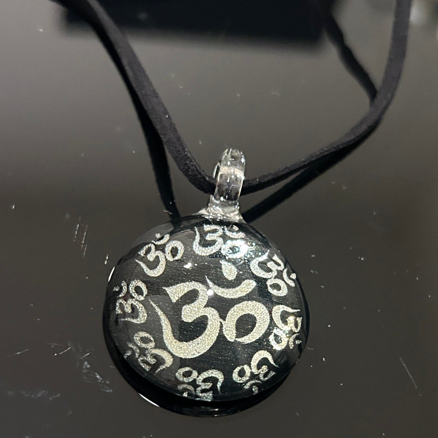 Handmade round black dichroic glass pendant with silver Om symbols sacred mantra yoga meditation spiritual jewelry on black satin cord necklace