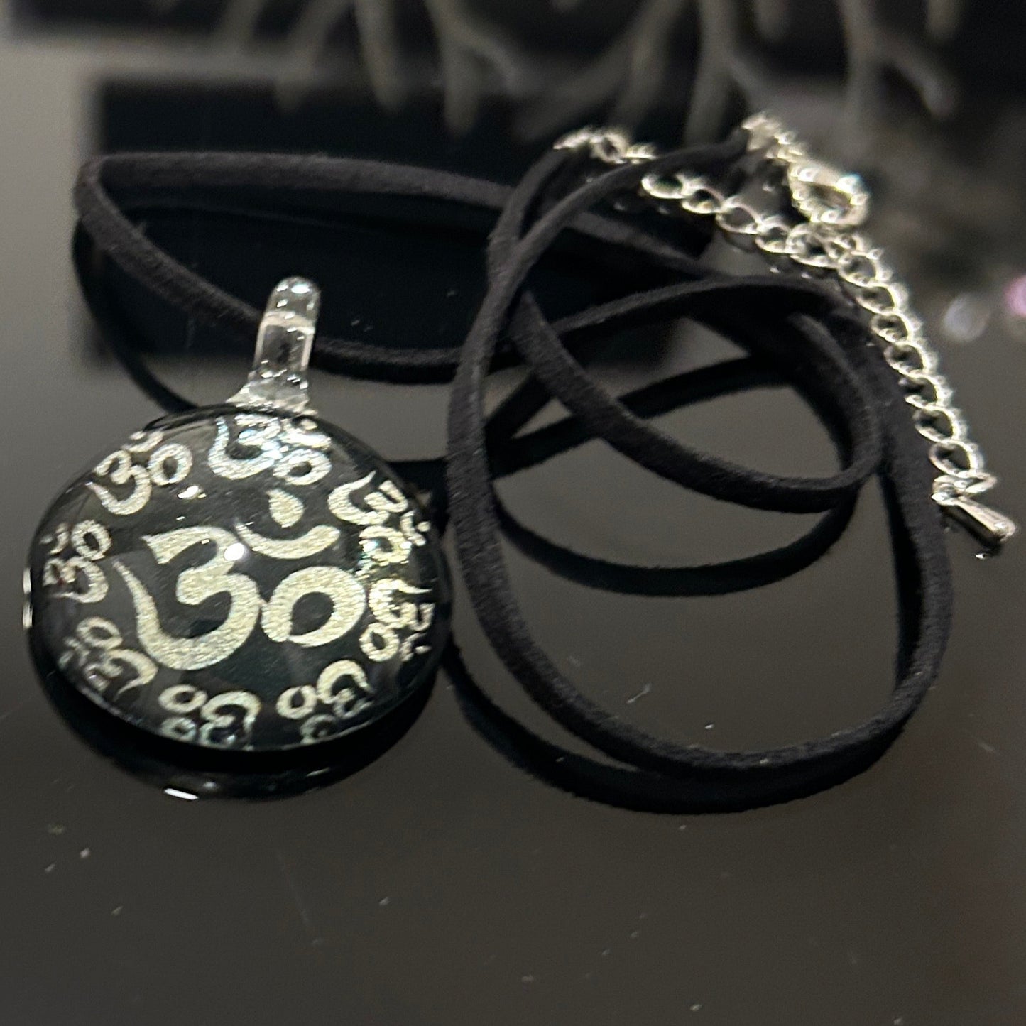 Handmade round black dichroic glass pendant with silver Om symbols sacred mantra yoga meditation spiritual jewelry on black satin cord necklace