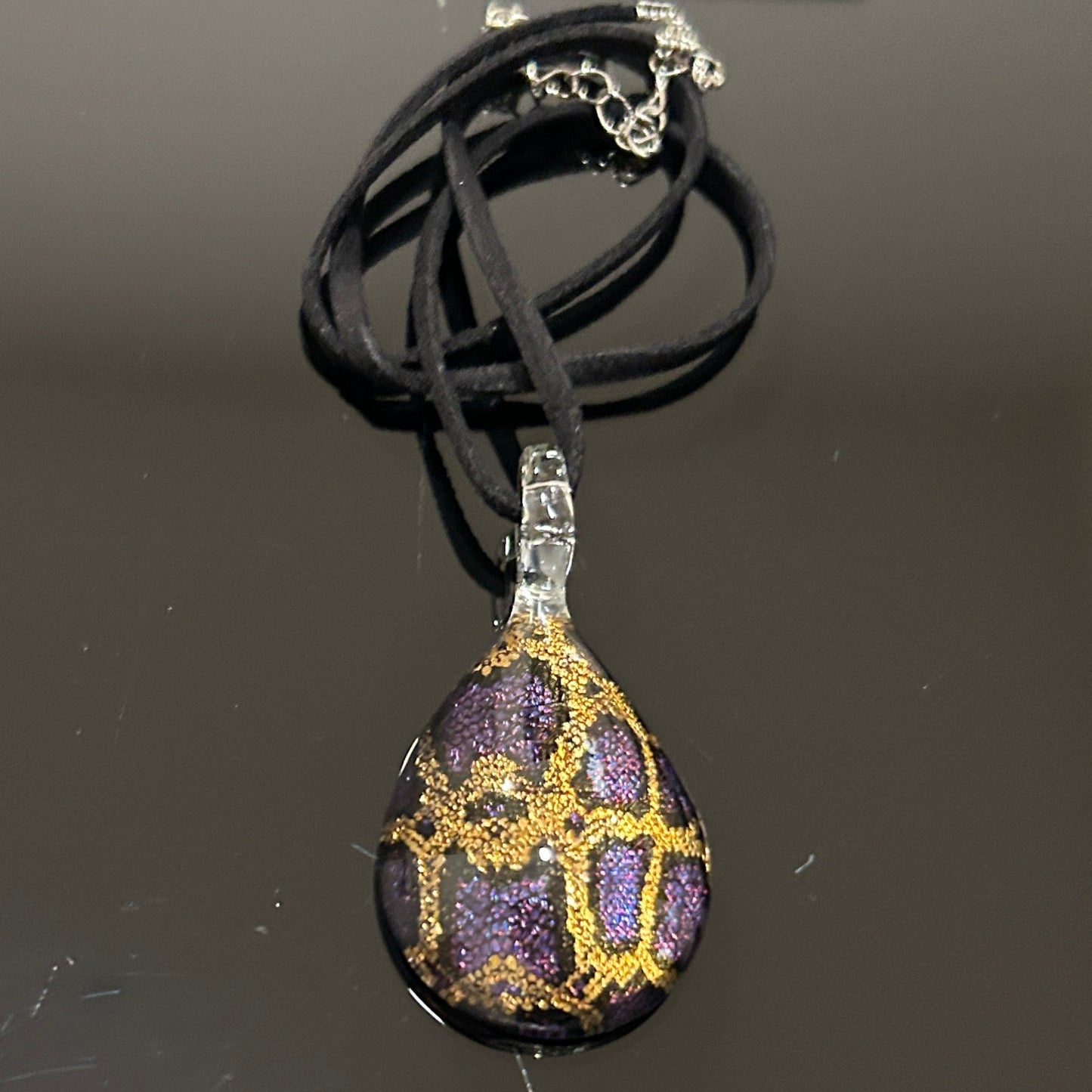 Handmade tree of life pendant in dichroic glass. 2 inches long, 1.25 inches wide. Blue and gold geometric design. Solid glass construction. 21" cloth cord included.